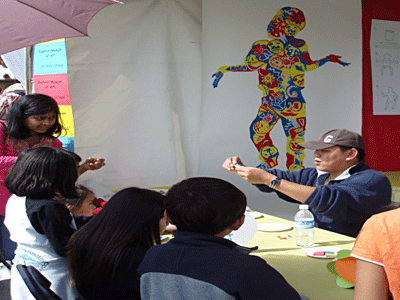 De Anza student intern Ha Bui shows participants how to make a dancing clay figure at the Euphrat Museum's Lunar New Year Unity Parade and International Fair booth.  